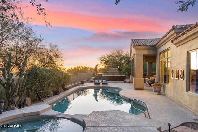 pool at dusk with a patio and an in ground hot tub