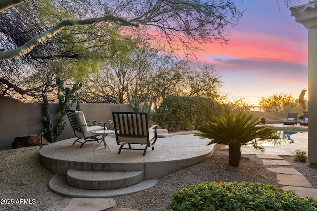 patio terrace at dusk featuring a fenced in pool