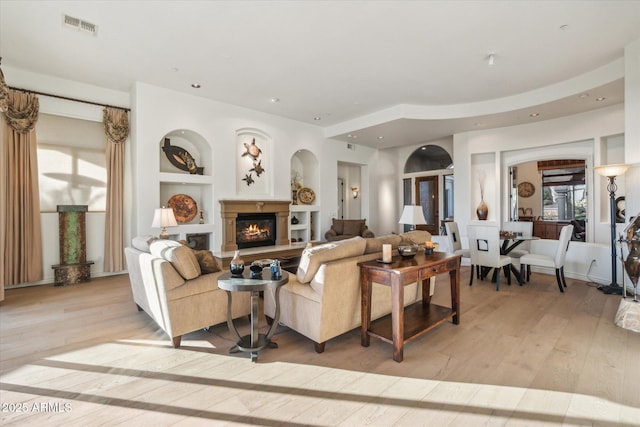 living room featuring built in shelves and light hardwood / wood-style flooring