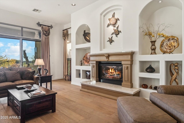 living room with built in features and light wood-type flooring