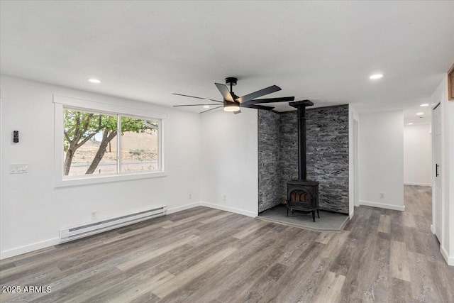 118 S 700th St E, Taylor, AZ 85939 - unfurnished living room featuring a baseboard heating unit, ceiling fan, a wood stove, wood finished floors, and recessed lighting
