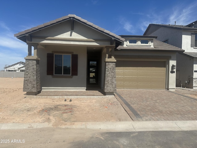 view of front of home with a tile roof, driveway, stucco siding, and an attached garage