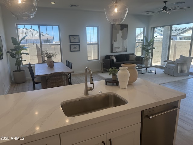 kitchen with white cabinets, visible vents, a sink, open floor plan, and stainless steel dishwasher
