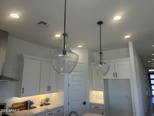details featuring decorative backsplash, white cabinets, visible vents, light countertops, and pendant lighting