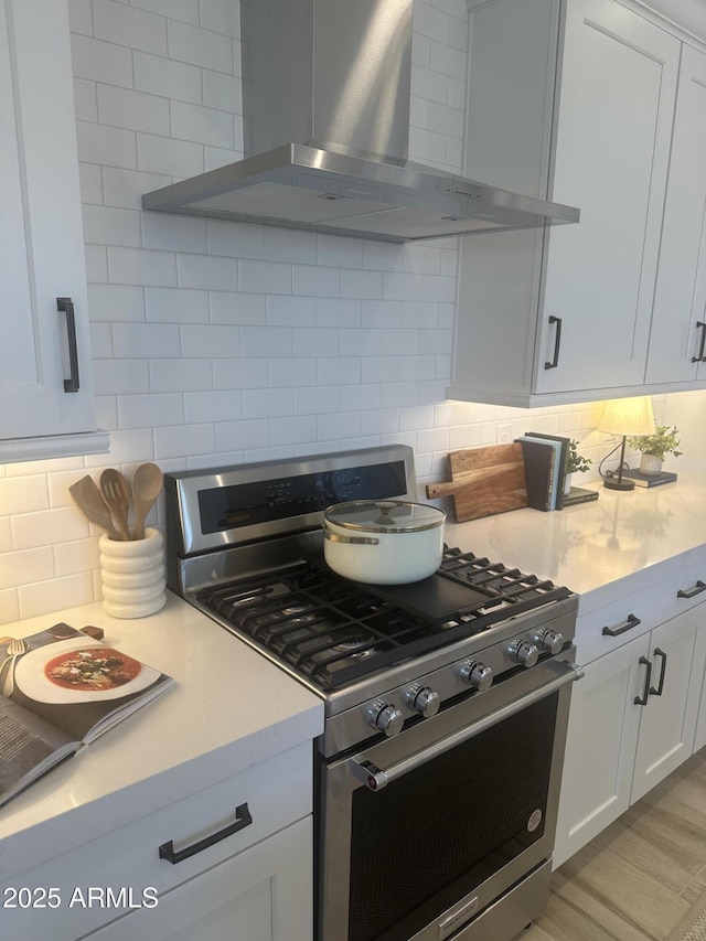 kitchen featuring white cabinetry, wall chimney exhaust hood, tasteful backsplash, and gas stove