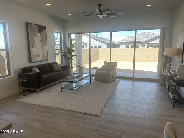 living room with a wealth of natural light, wood finished floors, ceiling fan, and recessed lighting