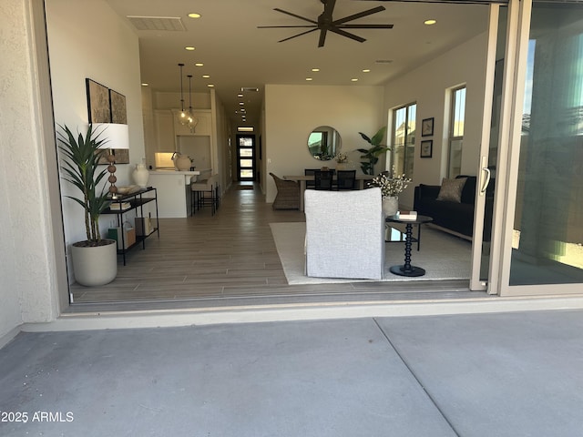 living room featuring concrete flooring, ceiling fan, visible vents, and recessed lighting