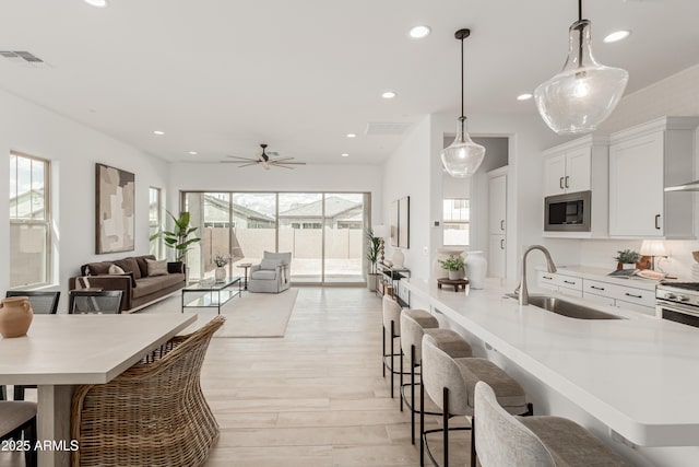 kitchen with recessed lighting, stainless steel microwave, a breakfast bar, a sink, and visible vents