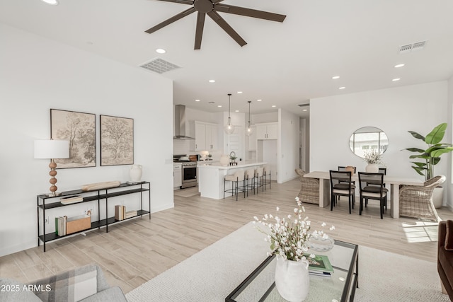 living room with visible vents, light wood-style floors, ceiling fan, and recessed lighting