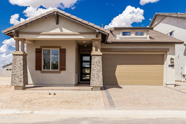 view of front facade featuring a tile roof, a garage, decorative driveway, and stucco siding