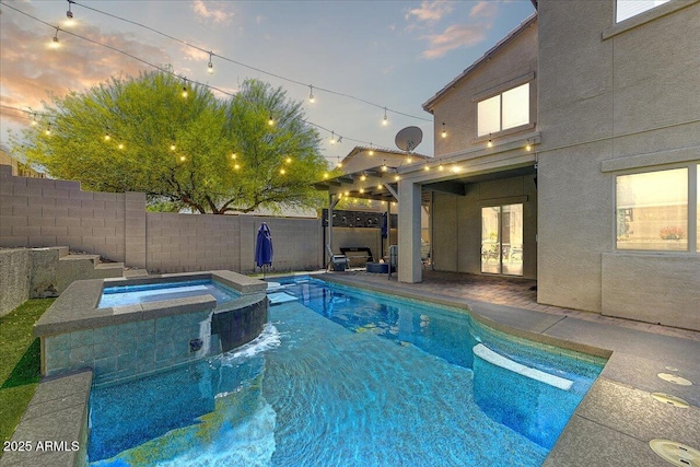 pool at dusk featuring a fenced backyard, a patio, a pool with connected hot tub, and french doors