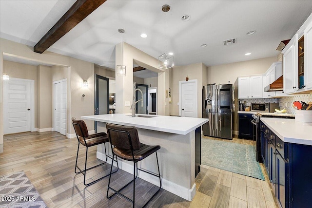 kitchen with a sink, stainless steel fridge with ice dispenser, extractor fan, decorative backsplash, and blue cabinets