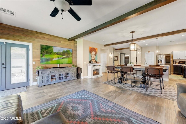 living room featuring visible vents, beam ceiling, and light wood-type flooring