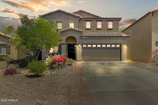 mediterranean / spanish-style home with an attached garage, stucco siding, driveway, and a tile roof