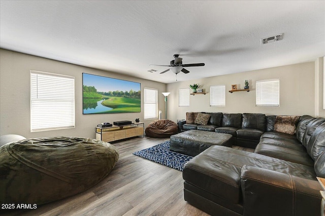 living room with visible vents, a ceiling fan, and light wood-style flooring