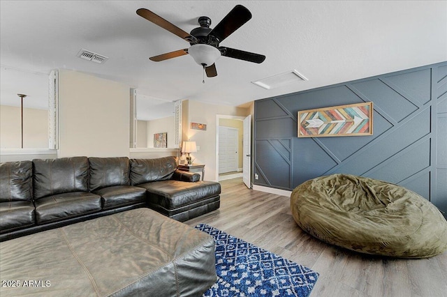 living area with visible vents, light wood-style floors, ceiling fan, and baseboards