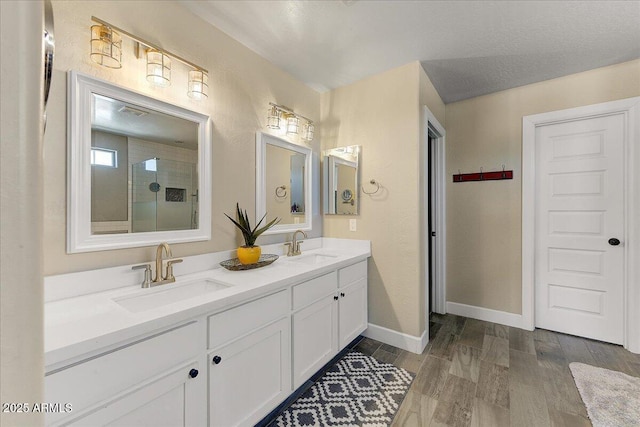 full bathroom with a sink, baseboards, double vanity, and wood finished floors
