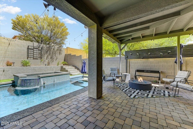 view of patio / terrace featuring a fenced backyard, a fire pit, and a pool with connected hot tub