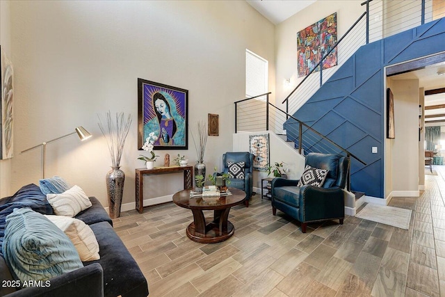 living area with baseboards, a high ceiling, stairs, and wood finished floors