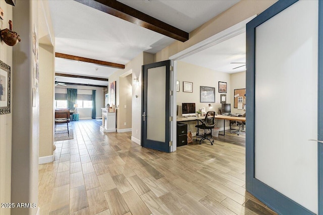 hallway featuring baseboards, beamed ceiling, and light wood-style flooring