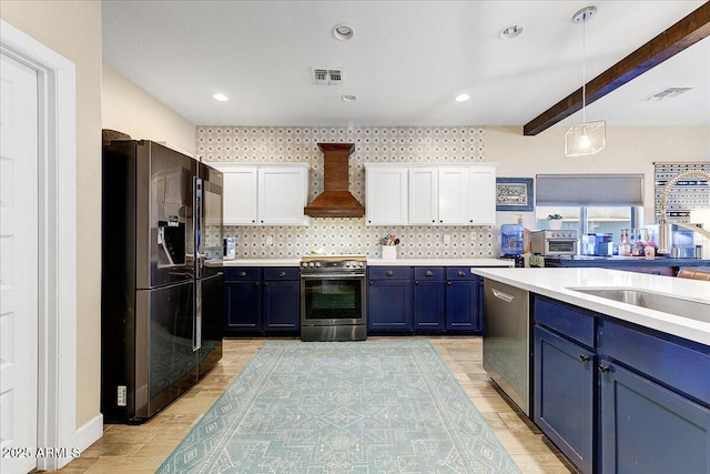 kitchen featuring blue cabinetry, stainless steel appliances, white cabinetry, visible vents, and custom exhaust hood