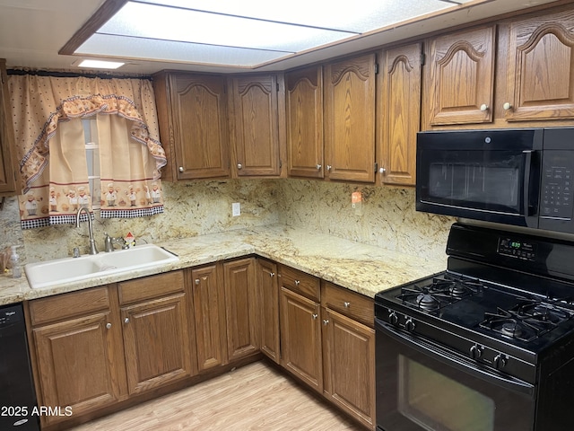 3115 N 26th St, Phoenix, AZ 85016 - kitchen with black appliances, a sink, decorative backsplash, light wood-style floors, and brown cabinetry