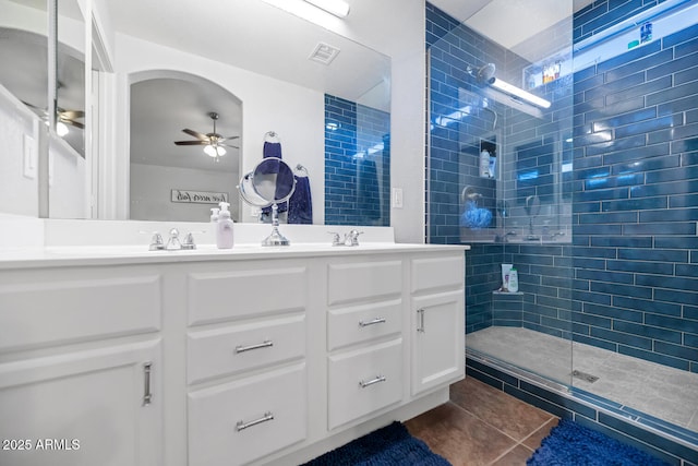 bathroom with ceiling fan, vanity, a tile shower, and tile patterned flooring