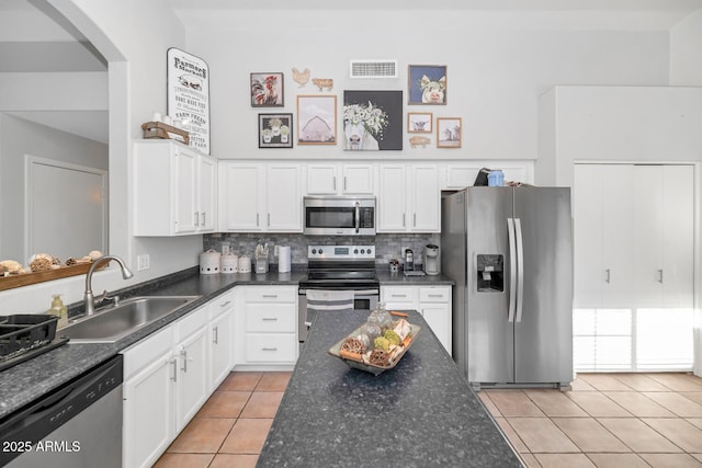 kitchen with tasteful backsplash, sink, white cabinetry, appliances with stainless steel finishes, and light tile patterned floors