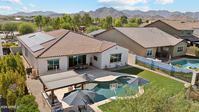 rear view of property with a mountain view, a patio, central AC unit, a fenced in pool, and a lawn