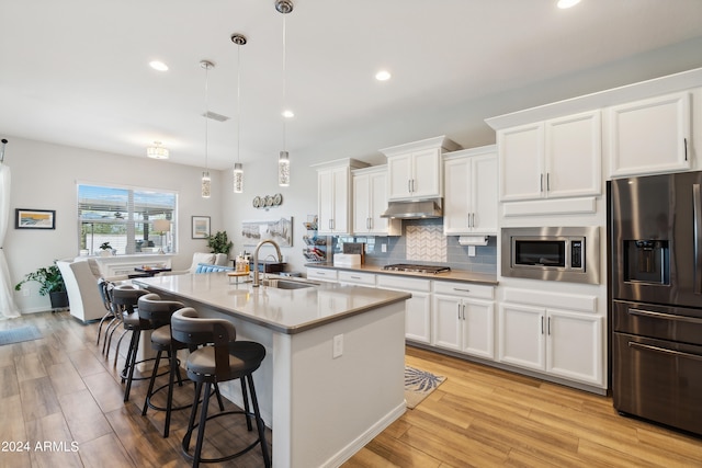 kitchen with appliances with stainless steel finishes, light hardwood / wood-style flooring, backsplash, white cabinetry, and sink