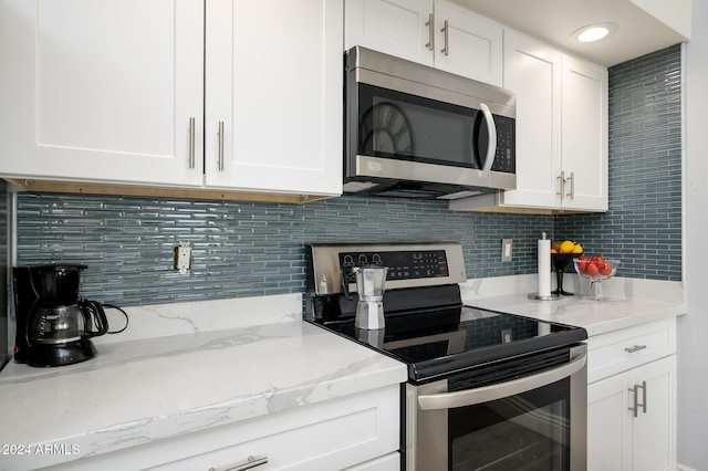 kitchen with backsplash, light stone countertops, white cabinetry, and stainless steel appliances