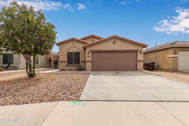 view of front of home featuring concrete driveway, a tiled roof, a garage, and stucco siding