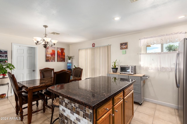 kitchen featuring stainless steel fridge, light tile patterned floors, ornamental molding, a notable chandelier, and a center island