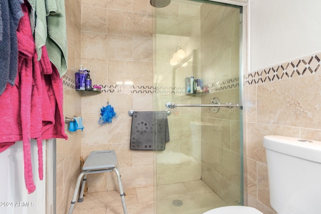 bathroom featuring a tile shower, toilet, and tile walls