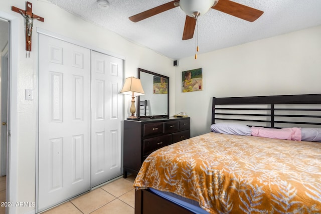 bedroom with light tile patterned floors, a textured ceiling, a closet, and ceiling fan