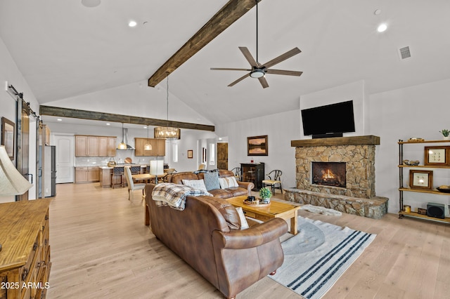 3441 S Del Aire Ct Unit 182, Flagstaff, AZ 86005 - living room with light wood-style flooring, a stone fireplace, ceiling fan, beam ceiling, and a barn door