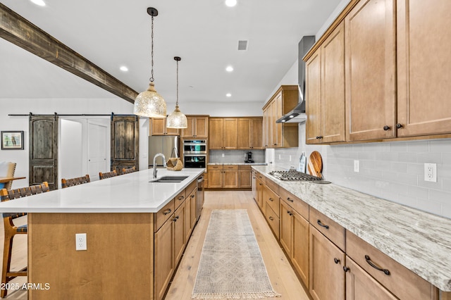 3441 S Del Aire Ct Unit 182, Flagstaff, AZ 86005 - kitchen with a sink, a barn door, stainless steel appliances, a kitchen breakfast bar, and light wood-type flooring