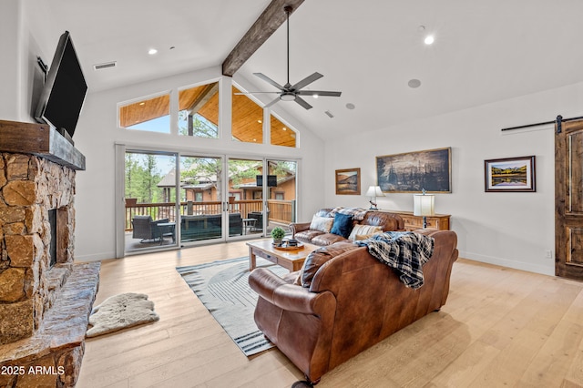 3441 S Del Aire Ct Unit 182, Flagstaff, AZ 86005 - living room with a barn door, a fireplace, beamed ceiling, ceiling fan, and light wood finished floors