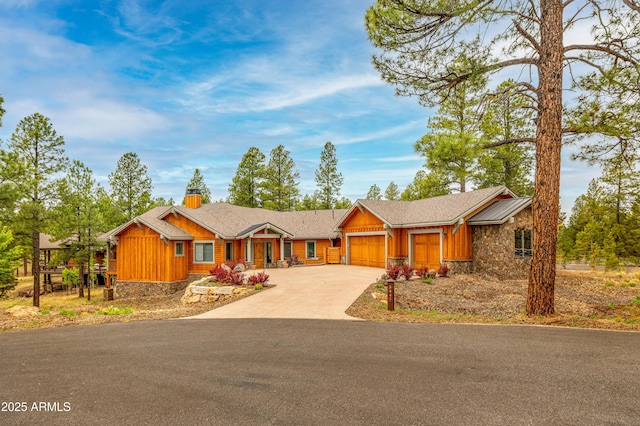 3441 S Del Aire Ct Unit 182, Flagstaff, AZ 86005 - view of front of house featuring stone siding, concrete driveway, a garage, board and batten siding, and a chimney