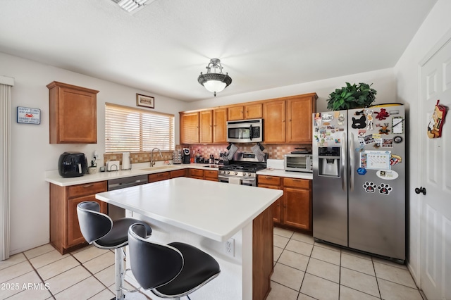 kitchen with tasteful backsplash, a center island, sink, appliances with stainless steel finishes, and a breakfast bar area