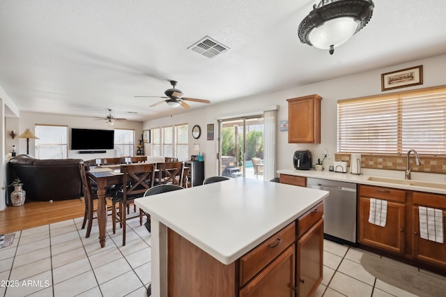 kitchen featuring ceiling fan, dishwasher, a center island, sink, and light tile patterned flooring