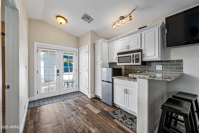 kitchen featuring vaulted ceiling, white cabinetry, appliances with stainless steel finishes, and tasteful backsplash