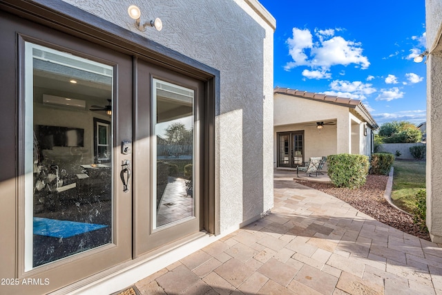 view of exterior entry with a wall mounted air conditioner, french doors, and a patio