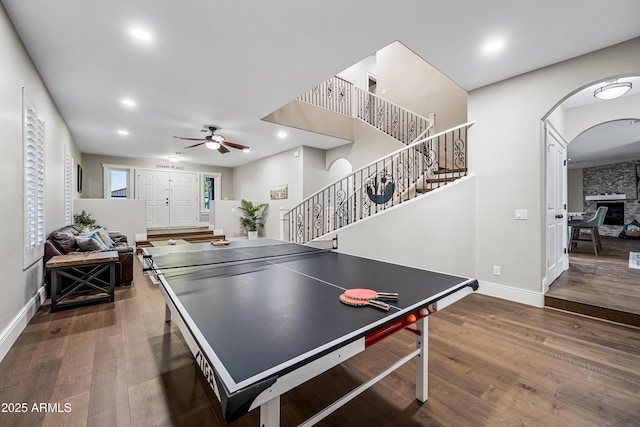 recreation room featuring ceiling fan, a fireplace, and dark wood-type flooring