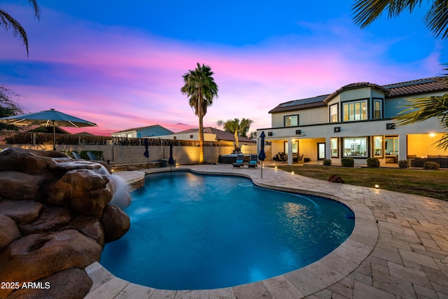 pool at dusk featuring a patio area