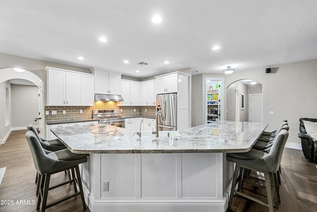 kitchen featuring white cabinets, a breakfast bar, a spacious island, and stainless steel appliances