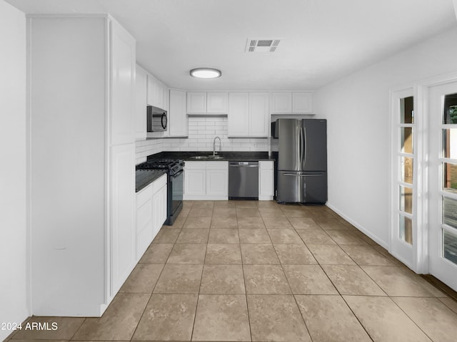 kitchen featuring white cabinetry, tasteful backsplash, light tile patterned floors, appliances with stainless steel finishes, and sink