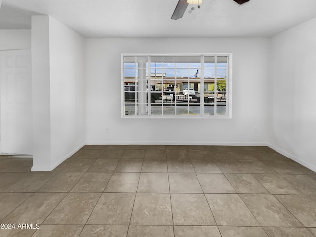 empty room featuring ceiling fan and tile patterned flooring