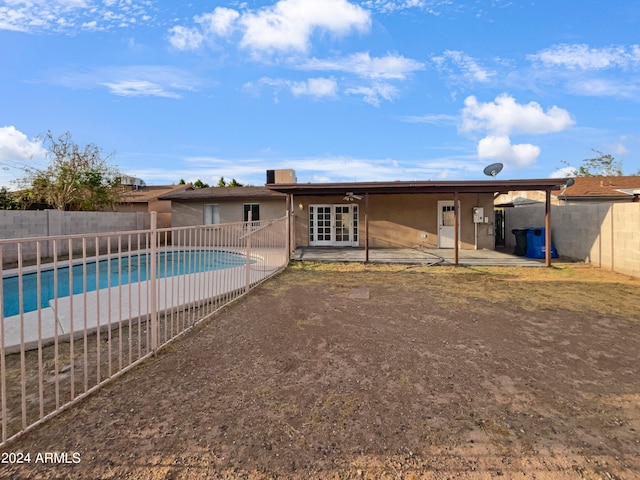 rear view of property featuring a fenced in pool and french doors