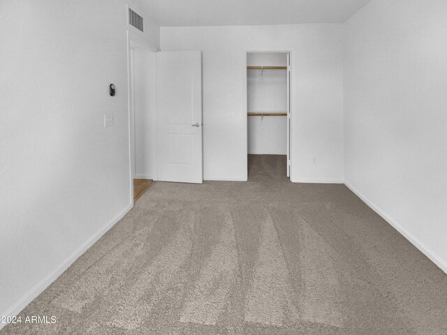 unfurnished bedroom with a closet, carpet floors, and a spacious closet